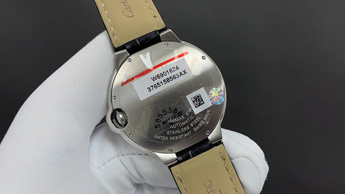 Cartier watch caseback with markings and iridescent logo, leather strap and clasp visible.