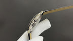 Cartier watch with metal case and crown on the side, black leather strap edge visible.