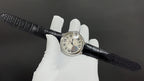 Cartier round wristwatch on black leather strap, Roman numeral dial and crown, side-on.