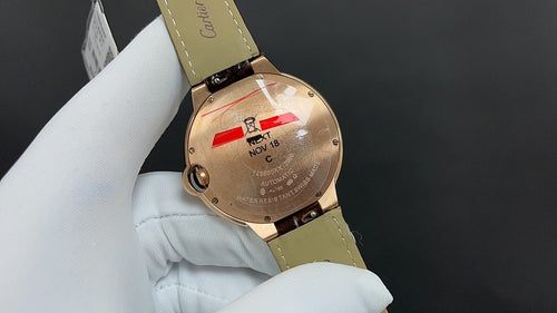 Cartier watch caseback with date markings, gold-tone finish, tan leather strap