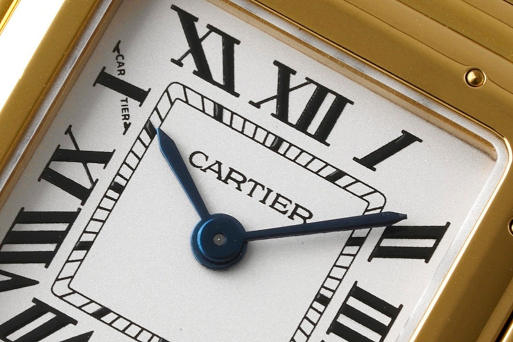 Gold-tone Cartier Tank watch dial close-up with blue hour/minute hands