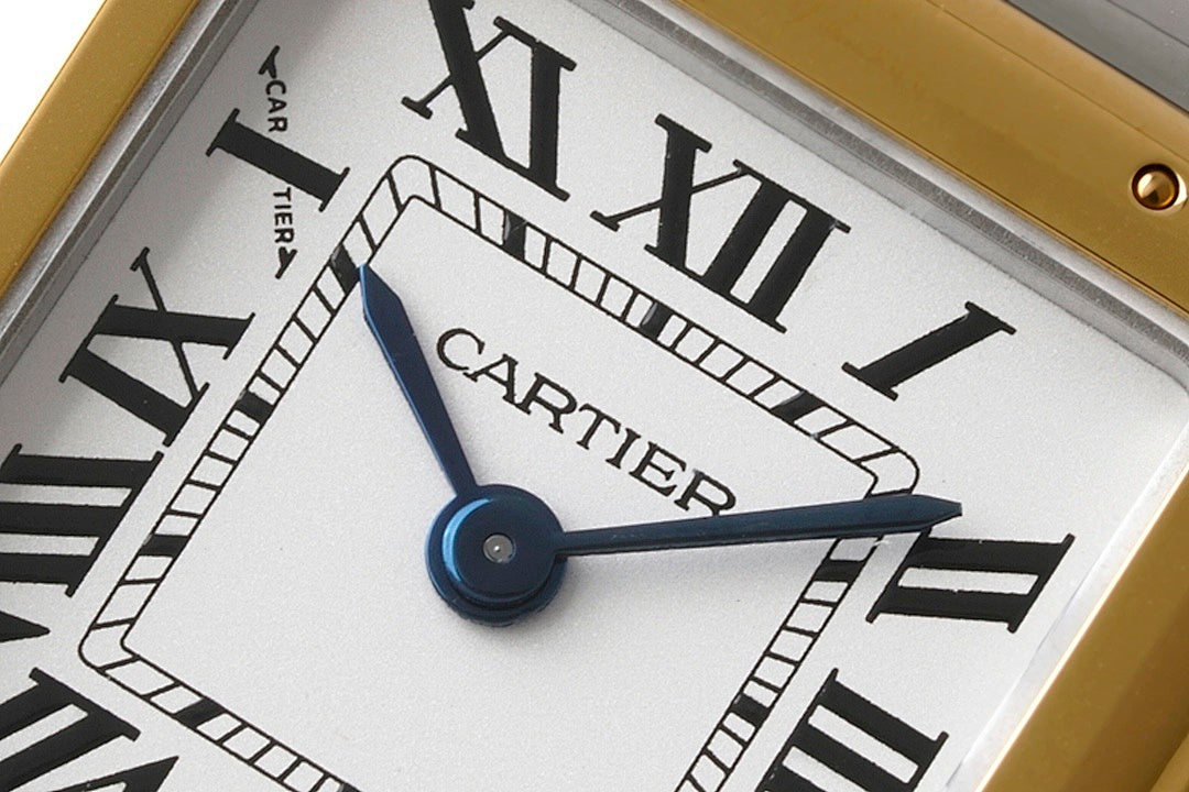 Cartier watch dial close-up showing CARTIER text, blue hand accent, Roman numerals