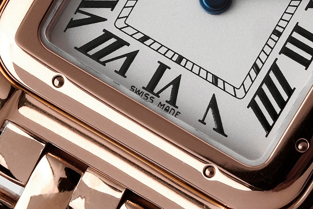 Cartier watch dial close-up with Roman numerals and black hands on a light face.
