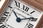 Cartier watch dial close-up showing blue central hands and Roman numeral markers.