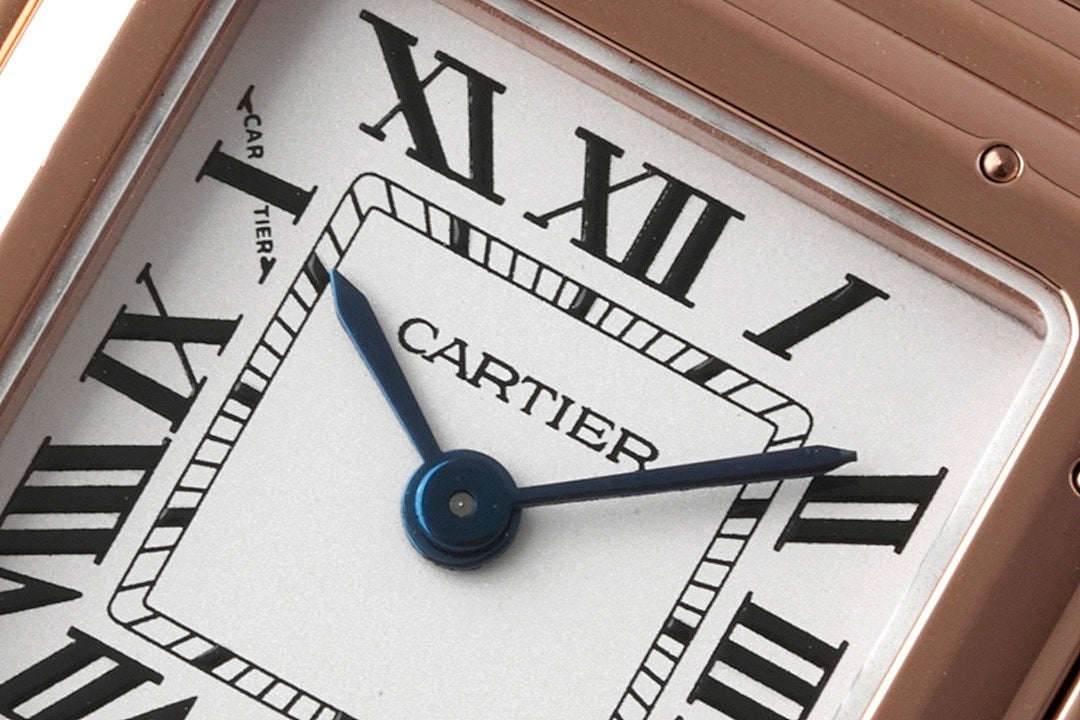 Cartier watch dial close-up showing blue central hands and Roman numeral markers.