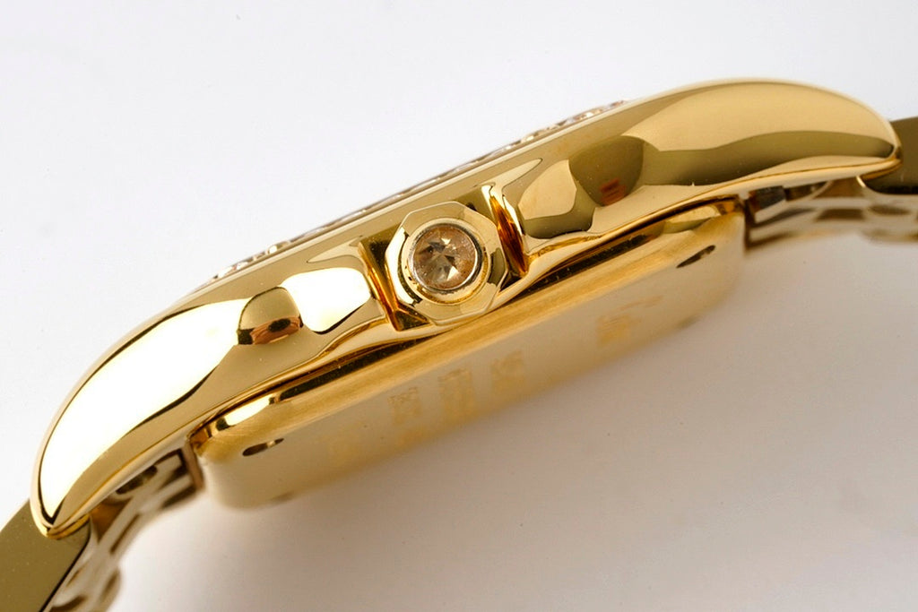 Gold-tone wristwatch crown area with round gem set on side of case