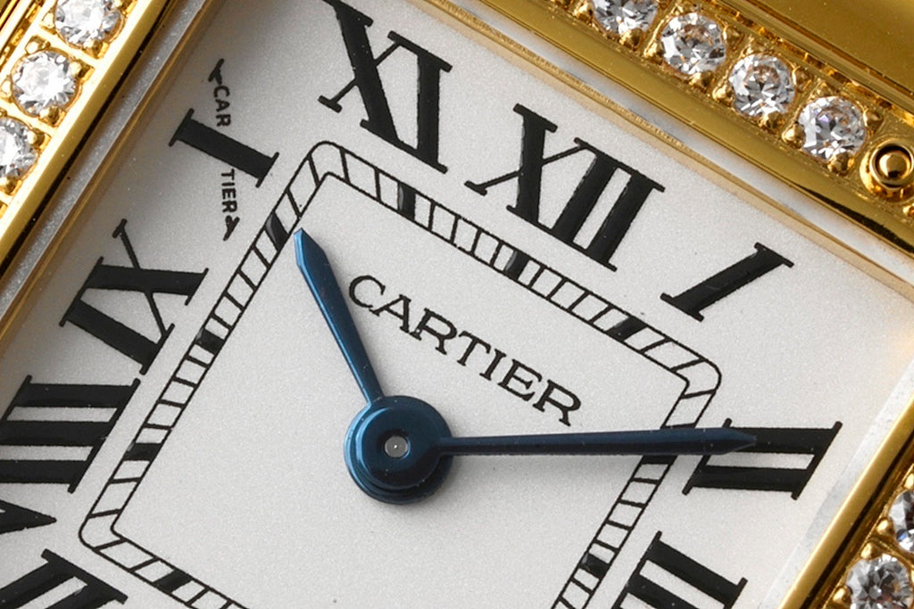 White dial wristwatch with Roman numerals, blue hands, and Cartier text