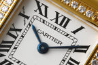 White dial wristwatch with Roman numerals, blue hands, and Cartier text