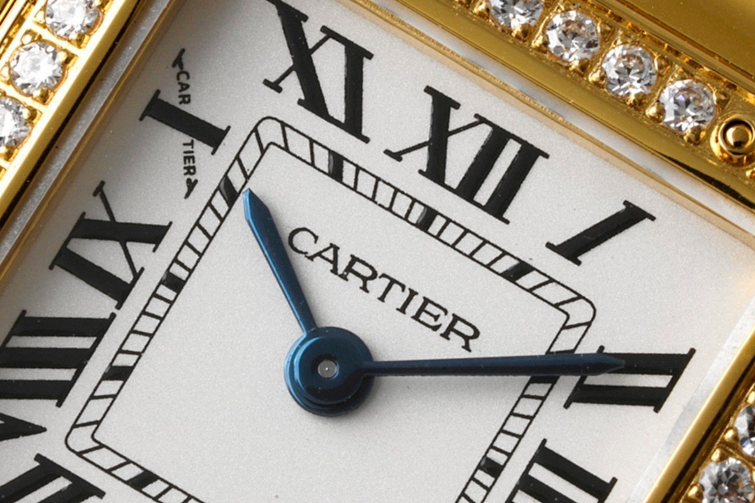 White dial wristwatch with Roman numerals, blue hands, and Cartier text