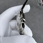 Cartier watch case side with round crown detail, glossy black leather strap.