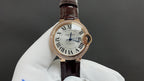 Cartier watch: white dial, Roman numerals, brown leather strap, rose gold case.