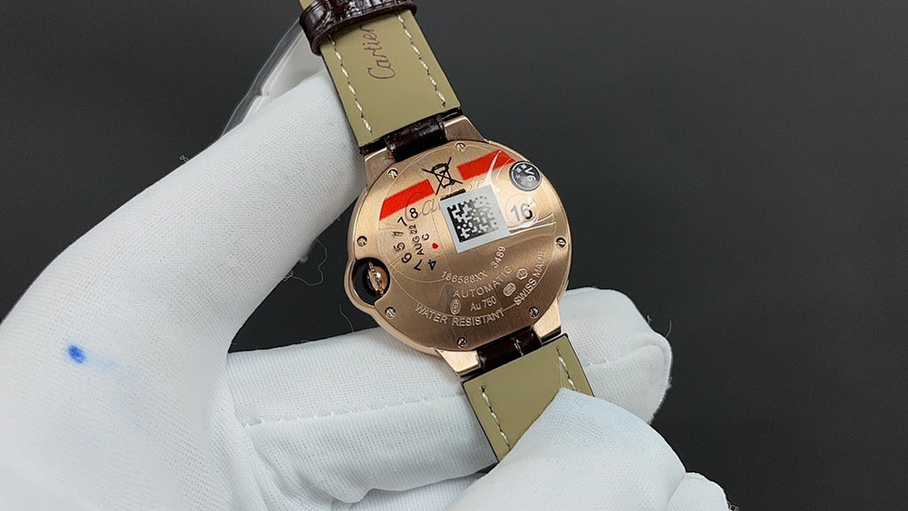 Cartier watch with gold-tone caseback detail and brown leather strap.