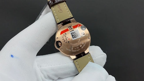 Cartier watch with gold-tone caseback detail and brown leather strap.