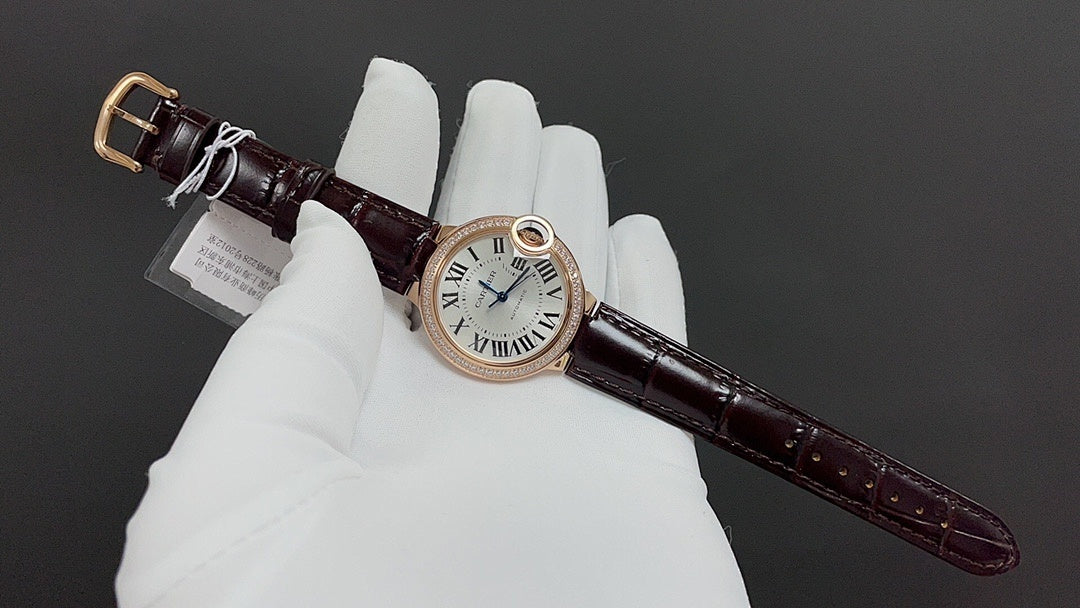 Cartier watch with brown leather strap and white dial, rose gold case, angled view.