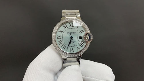 Cartier watch with silver bracelet, white dial with Roman numerals and diamond bezel.