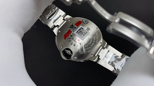 Cartier watch caseback with screws and red detail, showing metal bracelet links.