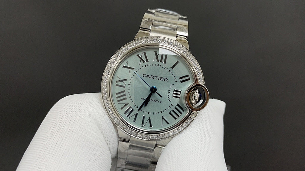 Cartier watch with teal-toned dial, Roman numerals, and silver jeweled bezel.