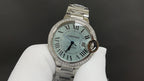 Cartier watch with teal-toned dial, Roman numerals, and silver jeweled bezel.