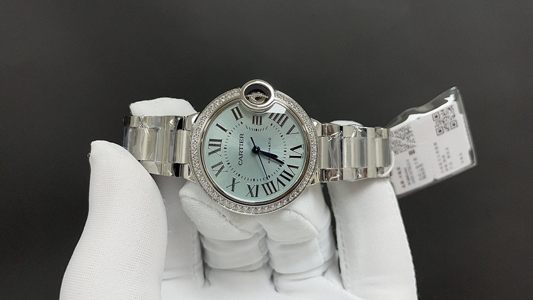 Cartier watch on wristband with open clasp, Roman numeral dial, and diamond bezel.