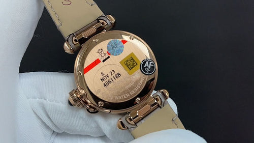 Gold-tone wristwatch back with leather strap, engraved case markings and screws