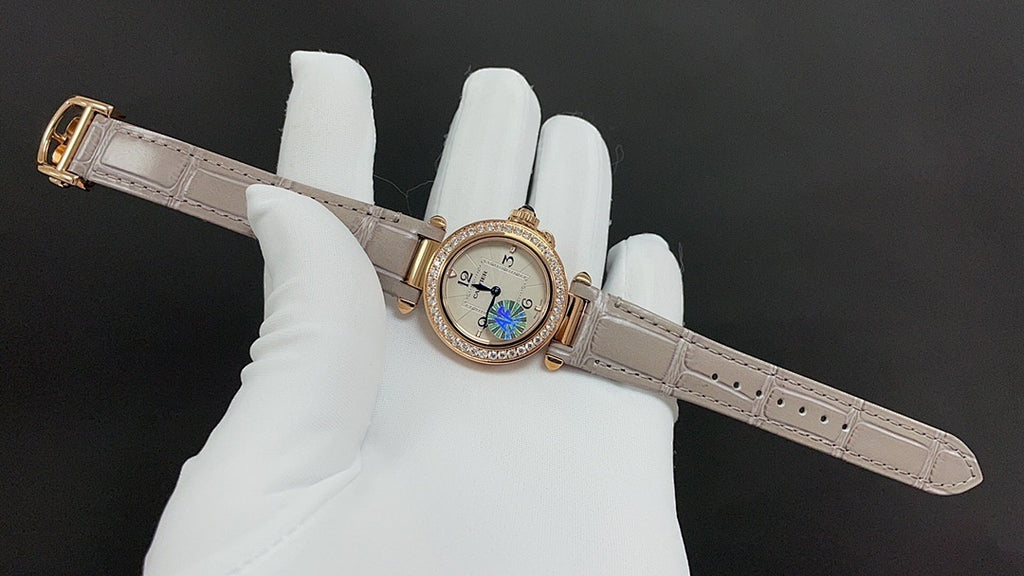 Round-faced wristwatch on a light leather strap with gold-tone case and blue detail