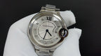 Cartier round watch with white dial, Roman numerals, and silver metal bracelet.