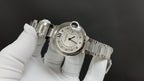 Cartier round watch with silver bracelet links and white dial, side and crown detail.