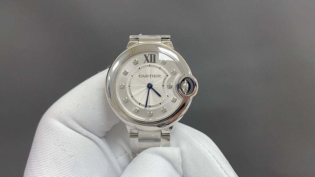 Cartier round wristwatch with white dial, Roman numerals, and steel bracelet on glove.