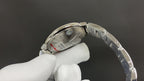 Cartier watch caseback from side, held in white glove, silver-tone finish