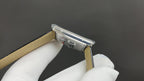 Wristwatch with tan strap lining and silver-tone rectangular case, side view