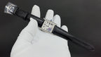 Wristwatch with black leather strap and silver-tone rectangular case, dial close-up