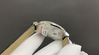 Wristwatch side view with stainless case back and tan leather strap