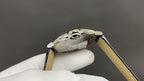 Wristwatch side view with crown and stainless case back, tan leather strap
