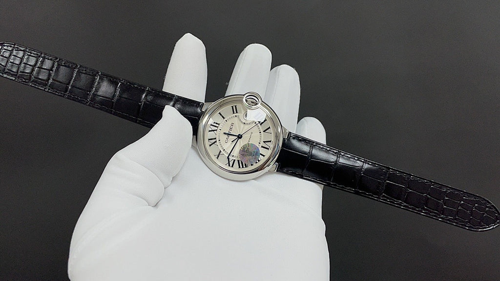 Wristwatch on black croc-texture leather strap, white dial on gloved hand