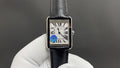 Cartier watch with silver rectangular case, black leather strap, Roman numeral dial