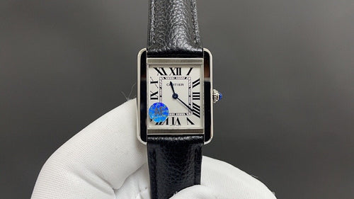 Cartier watch with silver rectangular case, black leather strap, Roman numeral dial