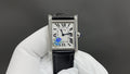Cartier watch with black leather strap and silver case, white dial with Roman numerals.