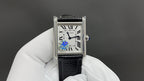 Cartier watch with black leather strap and silver case, white dial with Roman numerals.