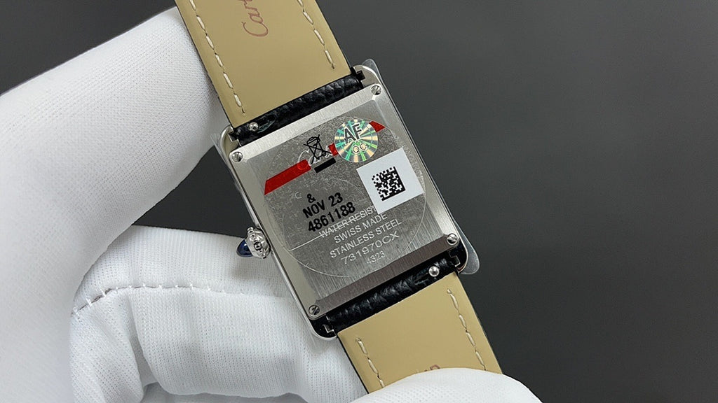 Cartier watch case back with black leather strap, with engraved text and serial details.
