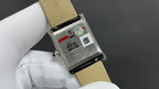 Cartier watch case back with black leather strap, with engraved text and serial details.