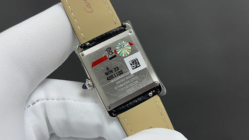 Cartier watch case back with black leather strap, with engraved text and serial details.