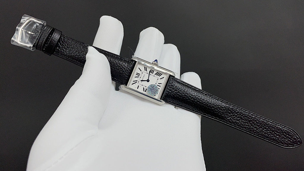 Cartier watch with black leather strap, rectangular silver case, and Roman numeral dial.