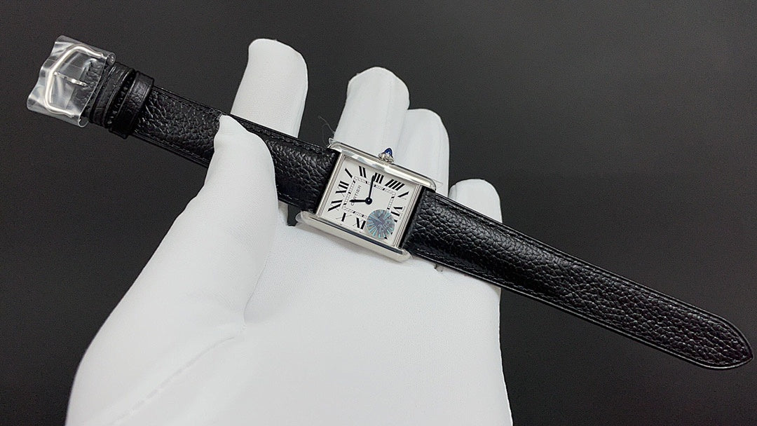 Cartier watch with black leather strap, rectangular silver case, and Roman numeral dial.
