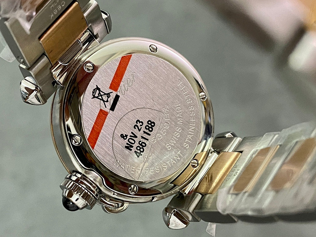 Cartier watch caseback detail with brushed metal finish, red/white stripe, and engraved text