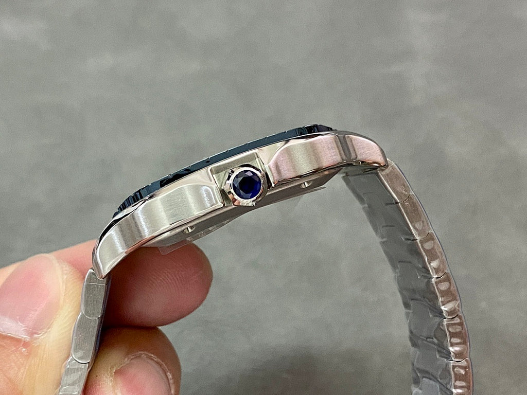 Cartier wristwatch case side with blue stone accent near crown, steel bracelet