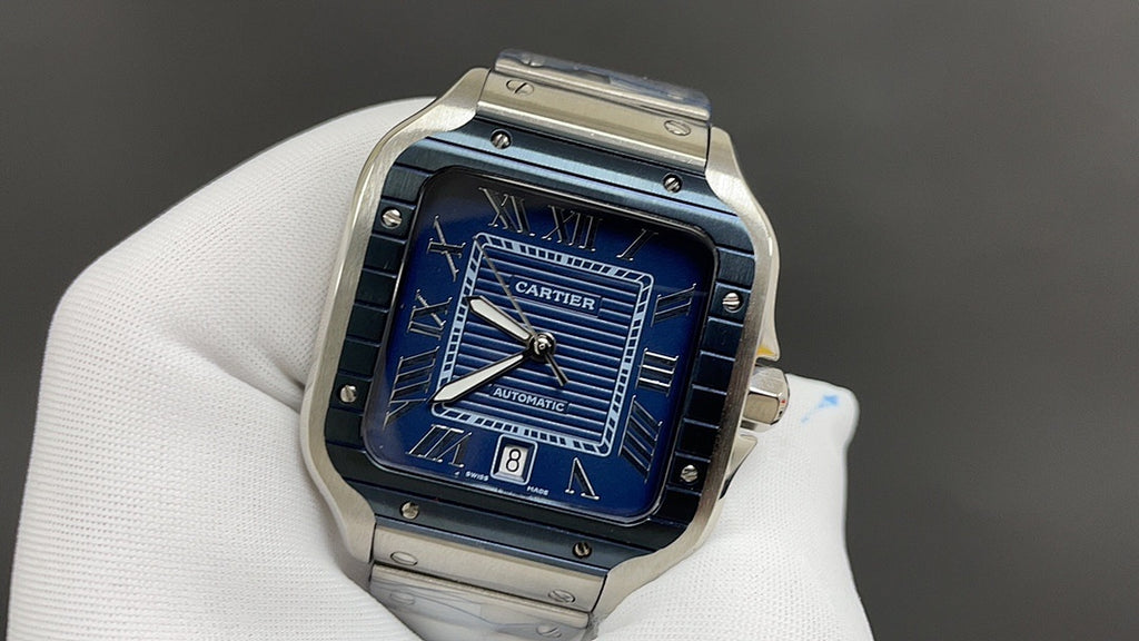 Stainless steel Cartier watch with blue dial, Roman numerals, and date window