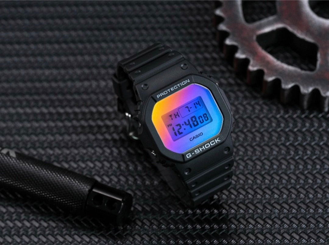 Casio G-Shock watch on textured surface with rainbow digital display