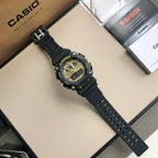 Black G-SHOCK wristwatch with gold dial and perforated strap, angled on display