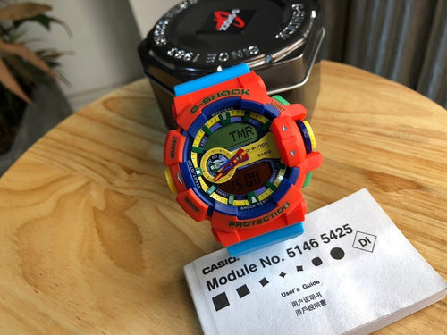 Casio watch with orange resin strap, round digital face, module label card
