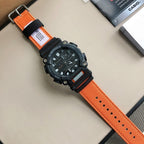 G-Shock wristwatch with orange fabric strap, black case, and metal pin buckle